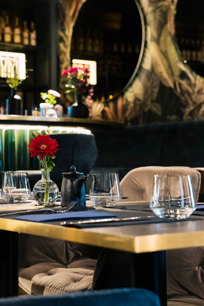 Elegant gedeckter Tisch mit roter Blume im Innenraum des Tiger Room Würzburg